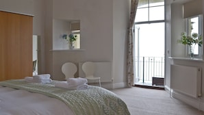 A bedroom with a bed, a chair, a window, and a radiator. - 2 bedroom accommodation in Torquay (Torquay)