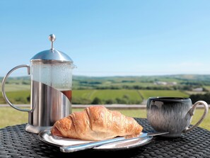 Une cafetière en métal, un croissant et une tasse sur une table, avec une vue panoramique.