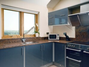 Une cuisine équipée d’un plan de travail en granit, d’un four à micro-ondes, d’un évier et d’une cuisinière.