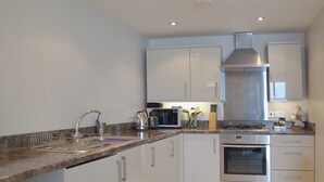Een moderne keuken met witte kasten, roestvrijstalen apparatuur en een granieten aanrecht.