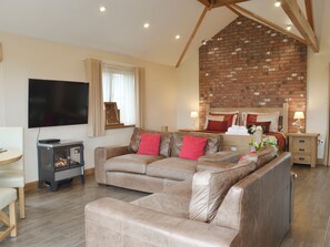 A modern living room with a sofa set, a flat-screen TV, a fireplace, and a brick accent wall. - 1 bedroom accommodation in Marhamchurch, near Bude (Marhamchurch, near Bude)