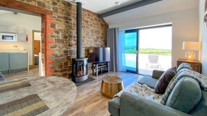 Een moderne woonkamer met een stenen muur, een open haard, een bank, een televisie en een balkon met uitzicht.