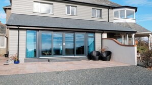 Une maison à deux étages avec une grande façade vitrée, un porche couvert et un petit garage attenant.