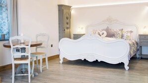Une chambre à coucher avec un lit blanc à baldaquin, une table en bois avec des chaises et un lustre.