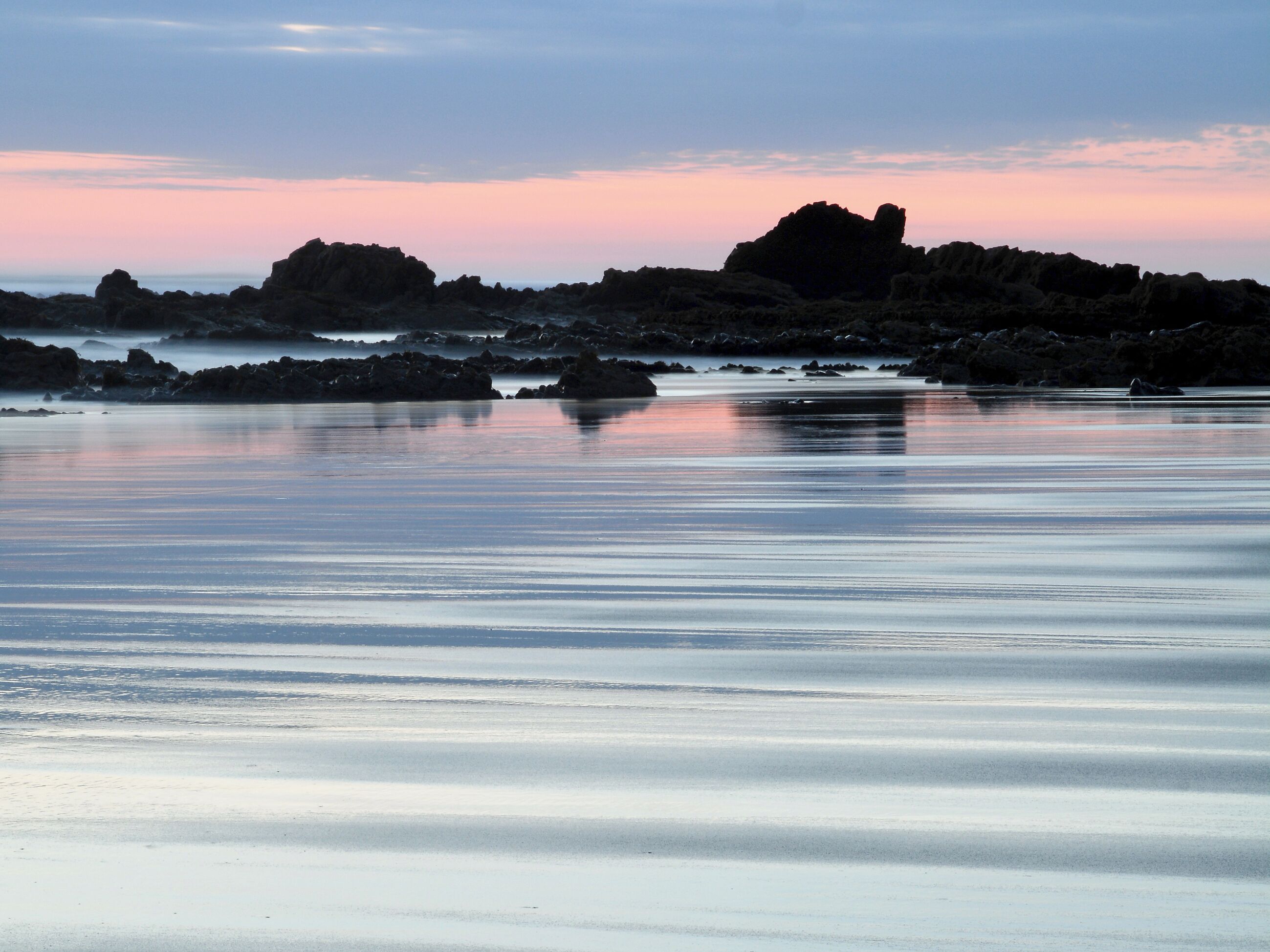 Une plage aux eaux calmes et aux formations rocheuses.
