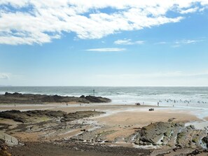 Une plage au paysage rocheux, avec un phare visible au loin.