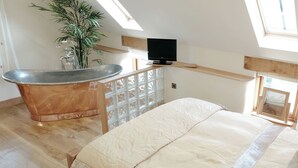 A room with a large bed, a bathtub, a television, and a potted plant. - 1 bedroom accommodation in Marhamchurch, near Bude (Marhamchurch, near Bude)