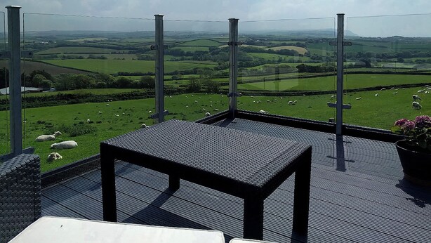 A balcony with a view of a green field with sheep, a metal railing, and a small table. - 1 bedroom accommodation in Marhamchurch, near Bude (Marhamchurch, near Bude)