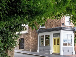 A building with a yellow door, a brick facade, and a window with a view of the sky. - 2 bedroom accommodation in Broseley (Broseley)
