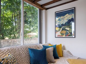 A room with a large window, a bed with patterned bedding, and a geometric artwork on the wall. - 2 bedroom accommodation in Broseley (Broseley)