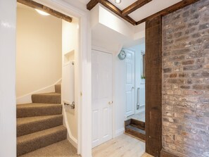 A staircase with carpeted steps leading to a white door, a brick wall, and a clock on the door. - 2 bedroom accommodation in Broseley (Broseley)