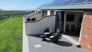 A house with a solar panel roof, a patio with outdoor furniture, and a view of the countryside. - 1 bedroom accommodation in Marhamchurch, near Bude (Marhamchurch, near Bude)