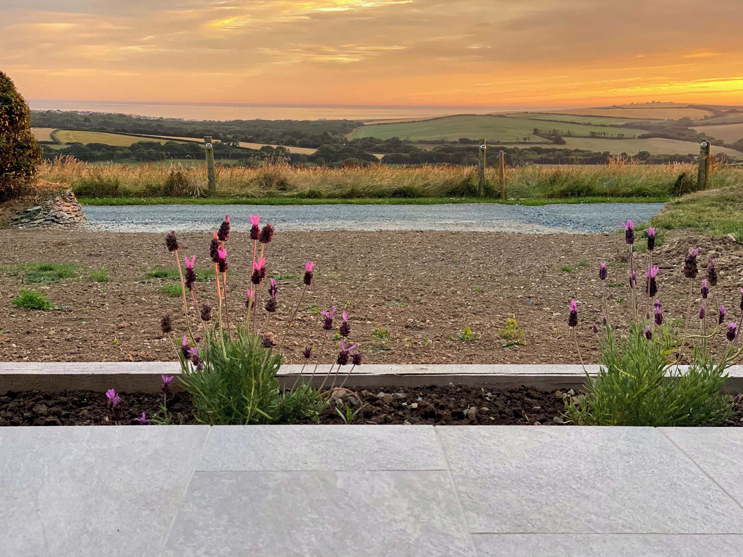 Un jardín con vistas a colinas ondulantes y una puesta de sol.