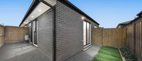 A modern house with a brick exterior, large windows, and a covered patio area.