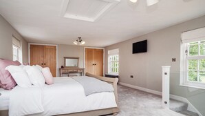 Ein Schlafzimmer mit Bett, Schminktisch, Spiegel, Fernseher und Fenster.
