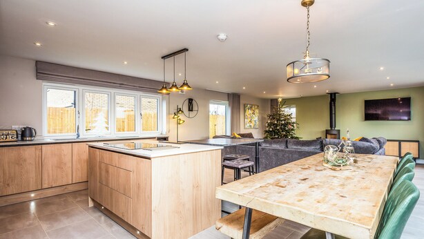 Una cocina moderna con una isla central, un comedor con mesa de madera y una sala de estar con sofá y un árbol de Navidad.