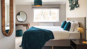 Un dormitorio con cama, mesita de noche, espejo, ventana y decoración en la pared.
