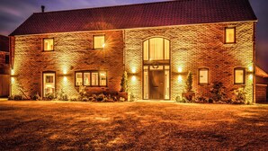 A brick building with a large arched entrance, multiple windows, and a well-lit front yard. - A stunning luxury holiday home with a swim spa to enjoy too. (Dunholme, near Lincoln)