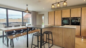 A modern kitchen with wooden cabinets, a central island, bar stools, and pendant lighting. - A stunning luxury holiday home with a swim spa to enjoy too. (Dunholme, near Lincoln)