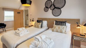 A hotel room with two beds, a wooden headboard, a wall art piece, and a window.