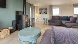 A living room with a fireplace, a sofa, a table, and a painting on the wall.