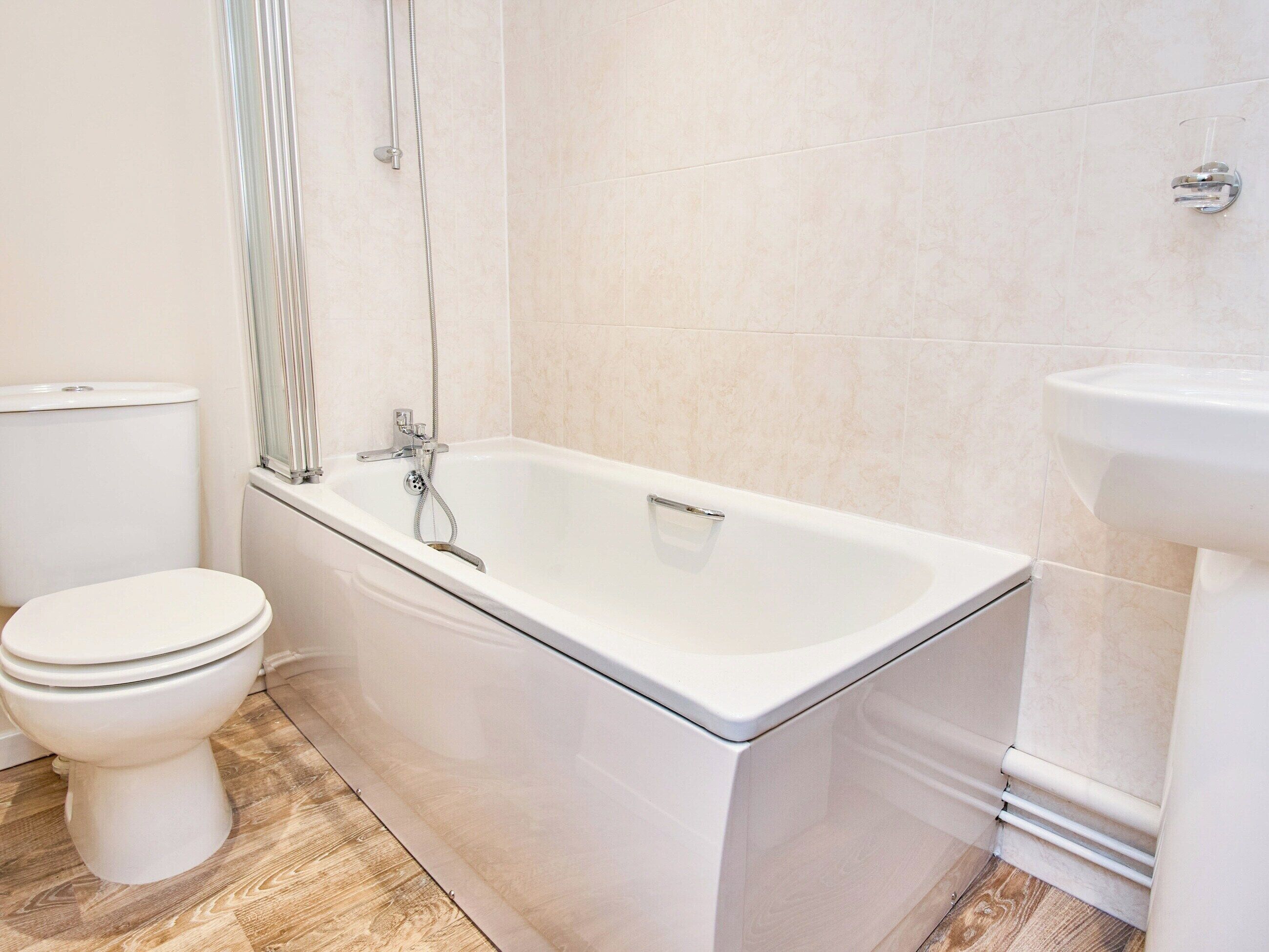 A bathroom with a white bathtub, toilet, and sink.