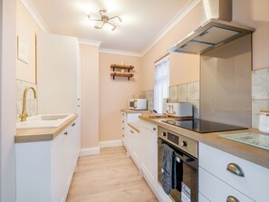 A modern kitchen with white cabinetry, a stainless steel range hood, a built-in oven, and a microwave. - 1 bedroom accommodation in Blue Anchor, near Minehead (Blue Anchor, near Minehead)