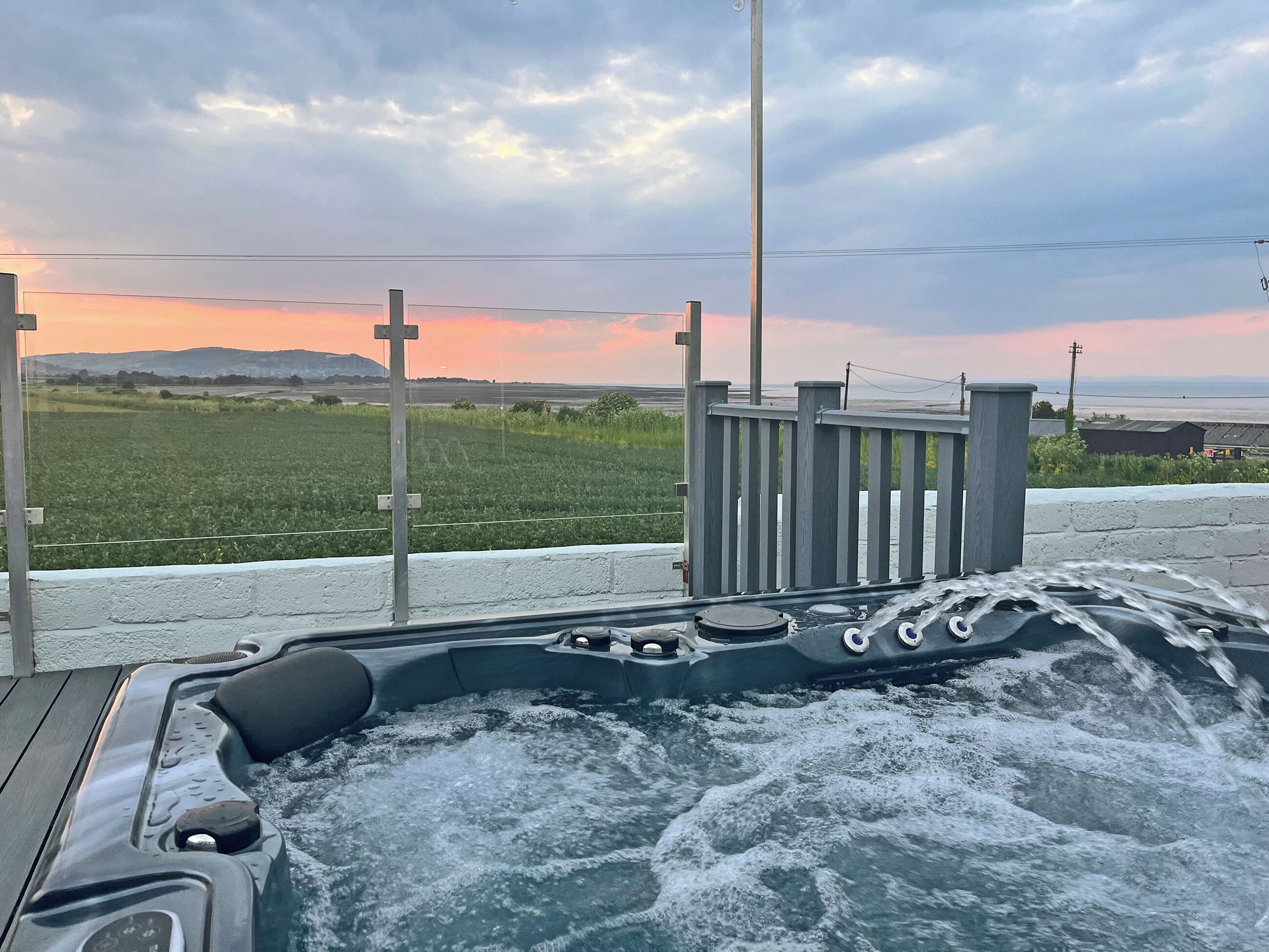 Un bain à remous sur une terrasse, avec vue sur un champ et des montagnes en arrière-plan.