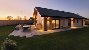 Ein modernes Haus mit Terrasse, Grill und einem großen Schiebeglastür.
