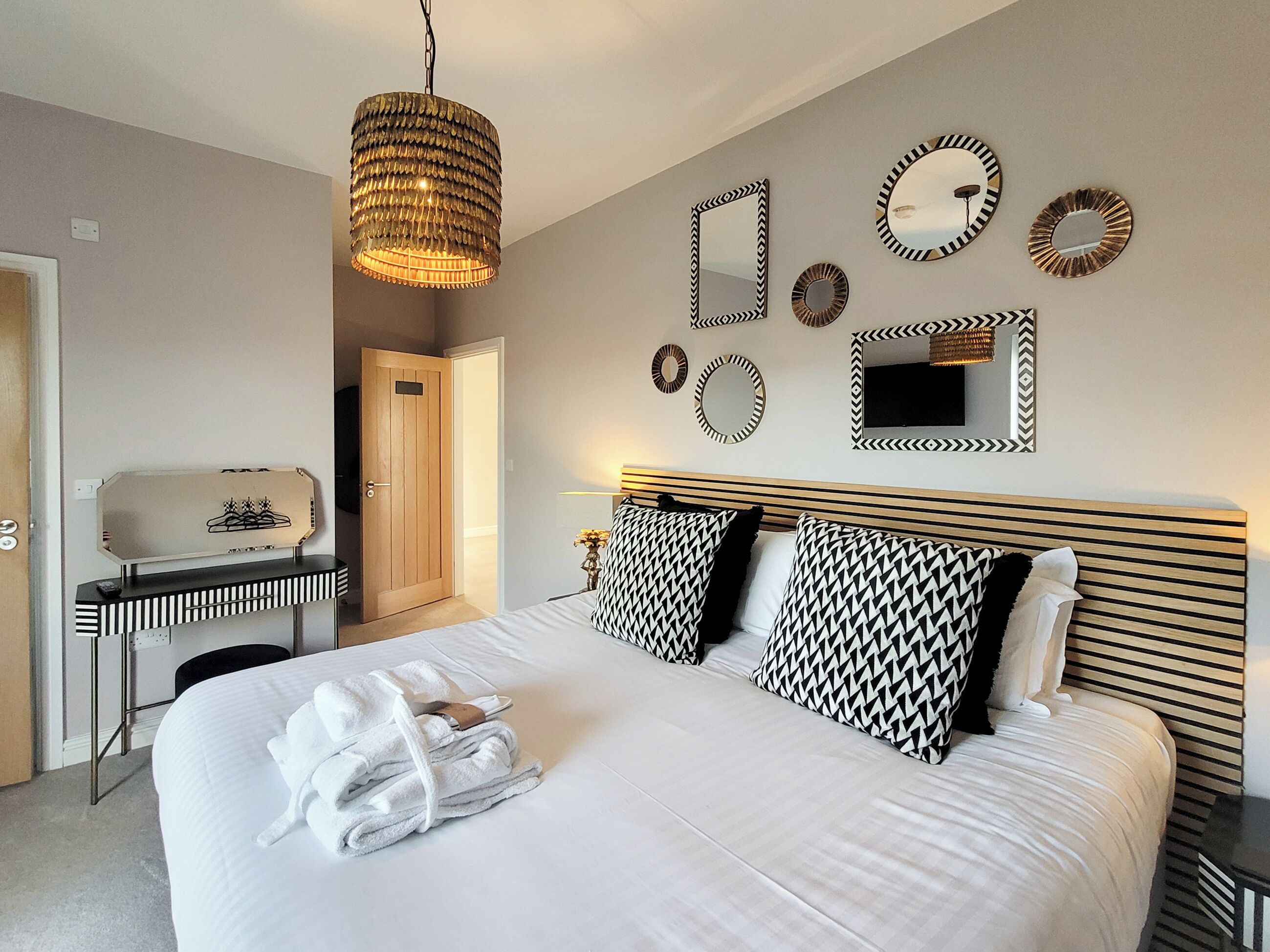 A hotel room with a bed, bedside table, and a mirror.