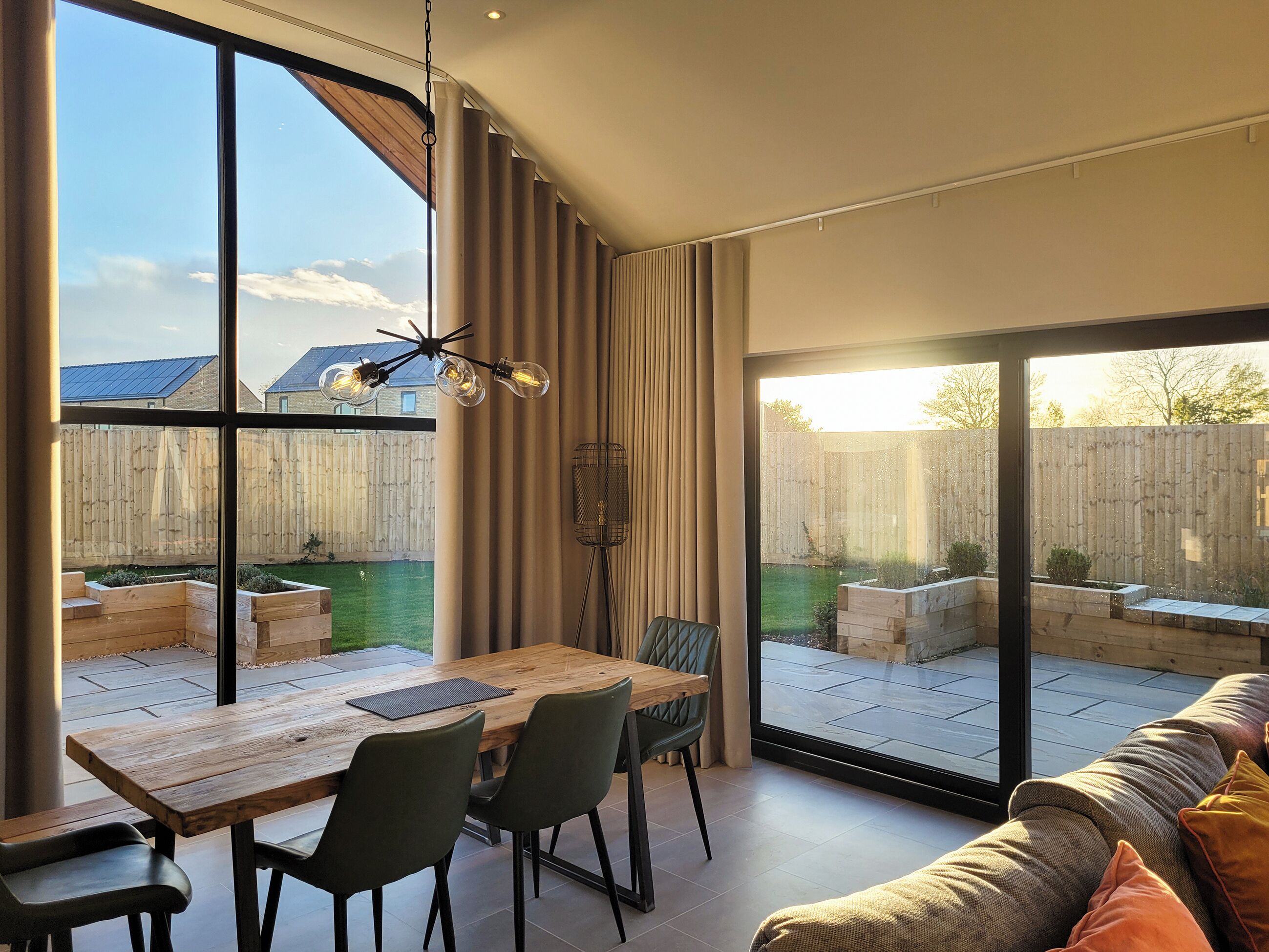 Un intérieur moderne comprenant un coin repas, de grandes fenêtres et une vue sur le jardin arrière.