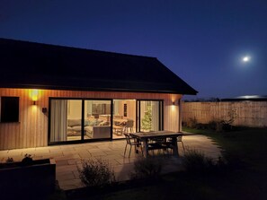 A modern house with a patio, sliding glass doors, and a wooden exterior. - Blue Iris Cottage - UKC4645 (Dunholme, near Lincoln)