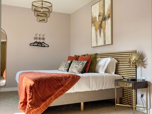 A neatly arranged bedroom with a bed, bedside table, and a wall-mounted artwork. - Blue Iris Cottage - UKC4645 (Dunholme, near Lincoln)