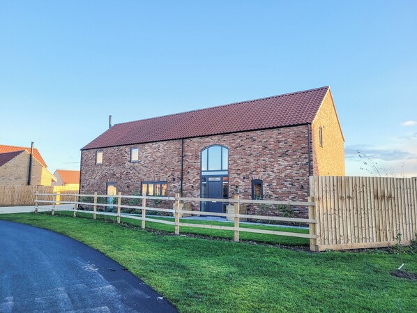 A brick building with a sloped roof, a wooden fence, and a paved driveway. - Chestnut House - UKC4650 (Dunholme, near Lincoln)
