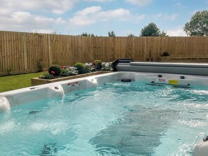 A hot tub with a wooden fence and flower beds in the background. - Chestnut House - UKC4650 (Dunholme, near Lincoln)