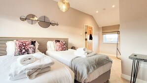 Une chambre avec deux lits, un luminaire au plafond, une porte et une fenêtre.