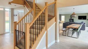 Un intérieur moderne avec un escalier en bois, un coin repas et une cuisine.