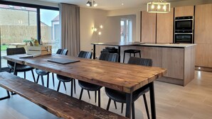 Eine moderne Küche mit Holzausstattung, einem eingebauten Backofen und einem Essbereich mit Holztisch und -stühlen.