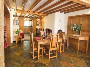 A dining area with a wooden table and chairs, a fireplace, and a bookshelf in the background. - Chestnut Cottage - UKC4654 (Swerford, near Chipping Norton)