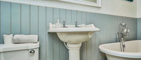 A bathroom with a pedestal sink, a toilet, and a clawfoot bathtub.