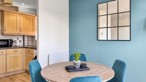 Eine moderne Küche mit Holzschränken, einer Mikrowelle und einem runden Tisch mit blauen Stühlen.