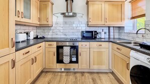 Eine moderne Küche mit Holzausstattung, einem Edelstahl-Dunstabzug, einer Mikrowelle und einem eingebauten Backofen.