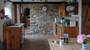 Eine rustikale Küche mit Holzschränken, einer Steinwand und einem Holztisch mit einem Croissant und einer Tasse.