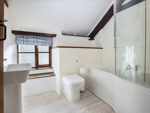 A bathroom with a window, a sink, a toilet, and a bathtub. - Jasmine Cottage - UKC4694 (Woodford, near Bude)