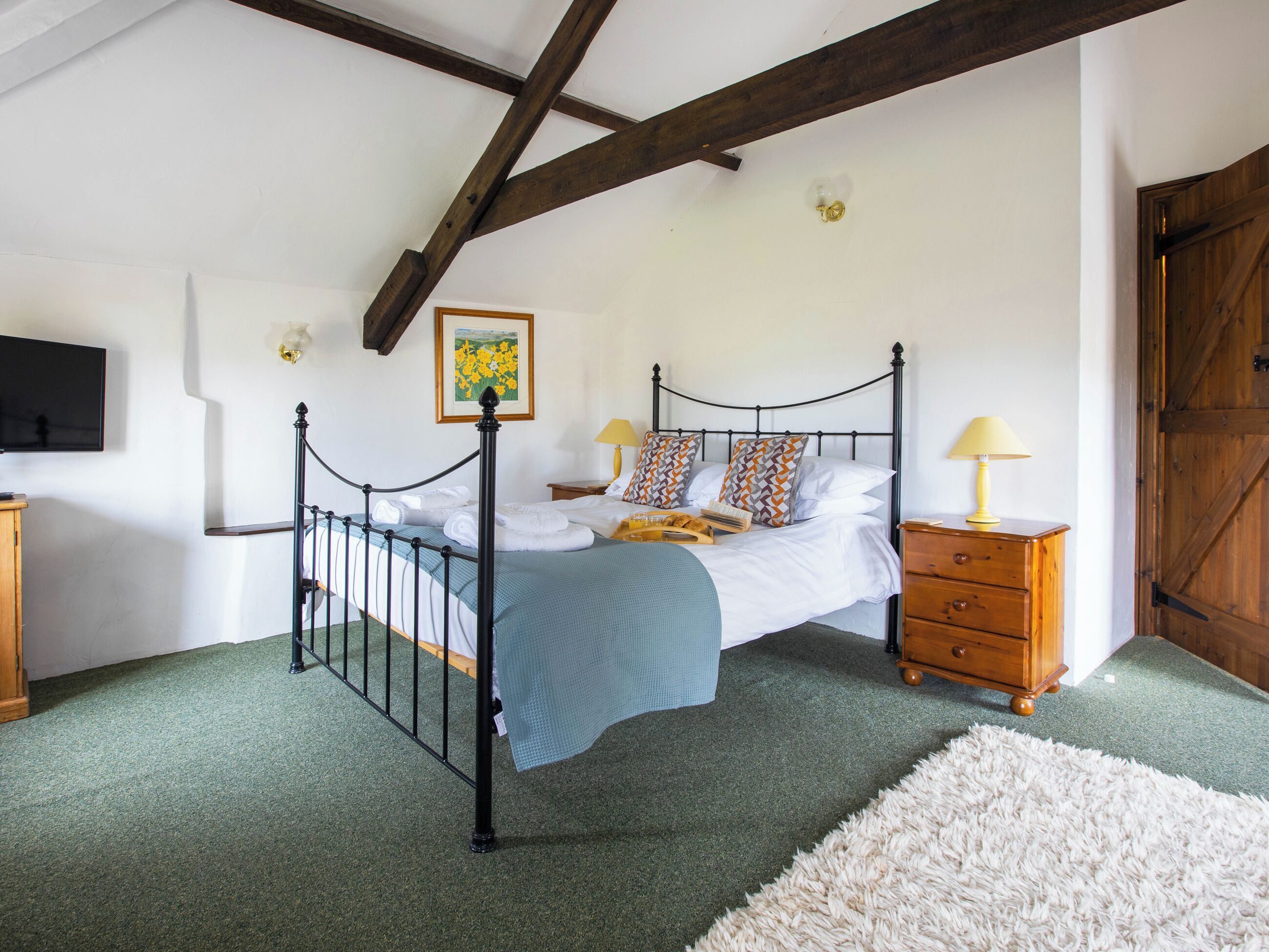 Une chambre à coucher avec un lit, des tables de chevet, une armoire en bois, une moquette verte et un tapis blanc.