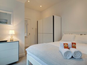 Ein Hotelzimmer mit einem Bett, einem Nachttisch mit Lampe, einem Kleiderschrank und einer Tür zu einem Badezimmer.