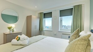 Una camera d'albergo con un letto, un armadio, uno specchio, una finestra con tende e vista sulla città.