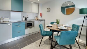 Una cucina moderna con zona pranzo, con un tavolo rotondo e sedie, una sveglia e una lampada.