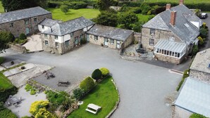 A rural property with stone buildings, a paved courtyard, and surrounding green fields. - The Stables - UKC4696 (Woodford, near Bude)