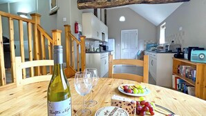 A dining table with a bottle of wine, two glasses, a plate of cheese, and a cheese knife. - The Old Dairy - UKC4698 (Kenilworth)